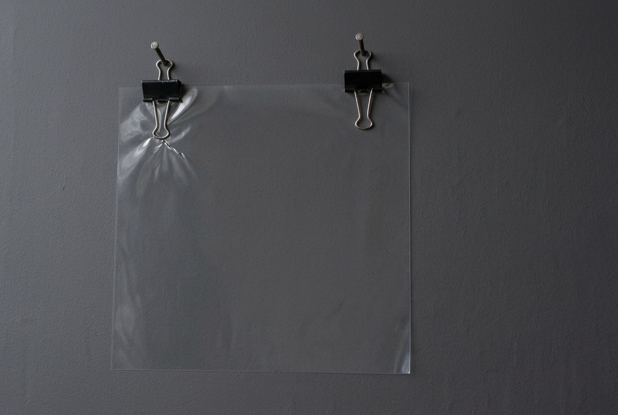 Clear film and binder clips against grey. AI-generated image; an invented arrangement.